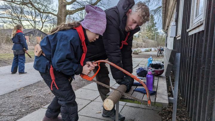 Spejderleder der hjælper en mini-spejder med at save